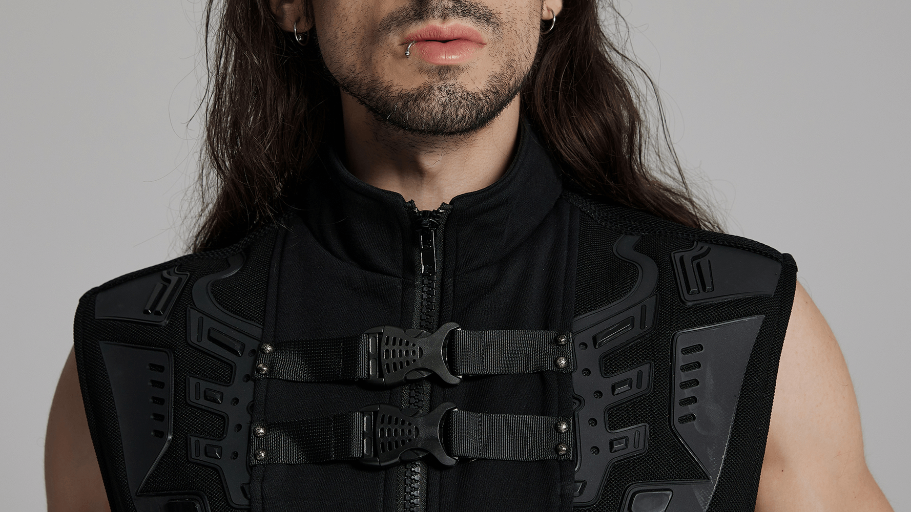 Close-up of a man wearing a futuristic cyberpunk vest with rubber armor and grid square buckles.