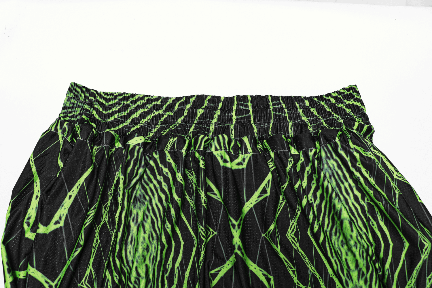 Futuristic geometric print harem pants with elastic waist in bold green and black design.