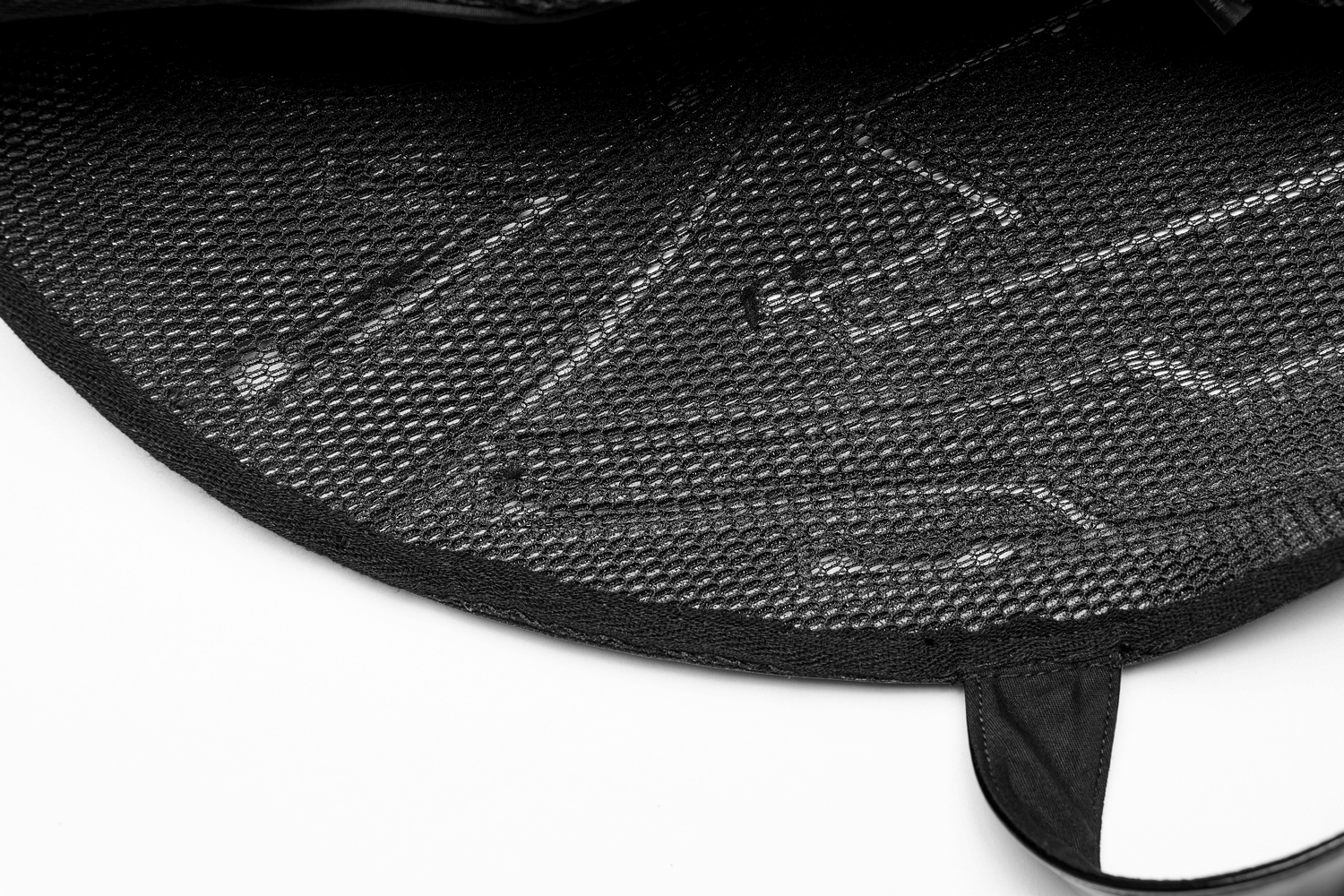 Close-up of a glossy black accessory featuring a textured mesh pattern inside.