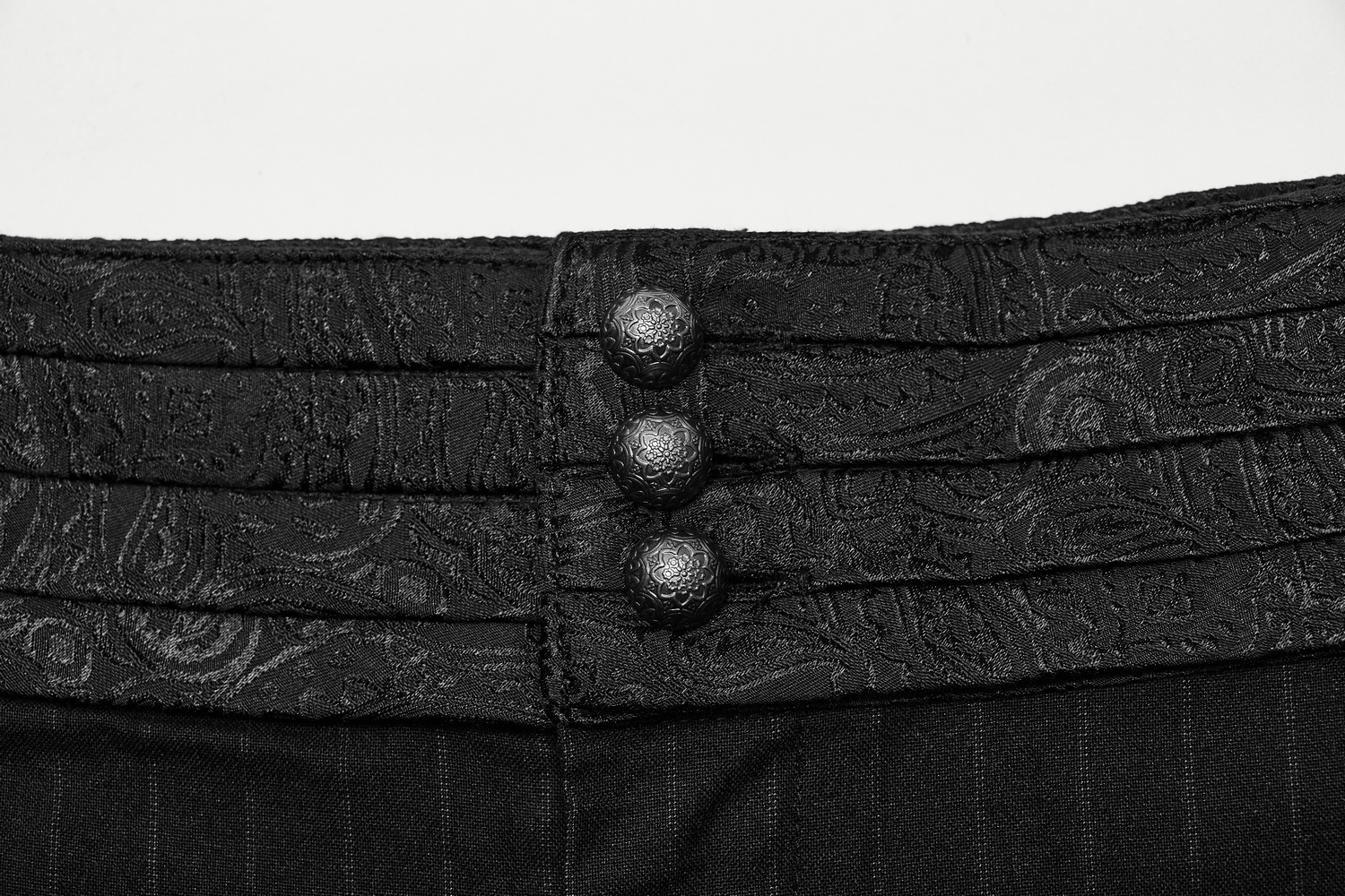 Close-up of the stylish layered waistband with decorative buttons on black striped steampunk pants.