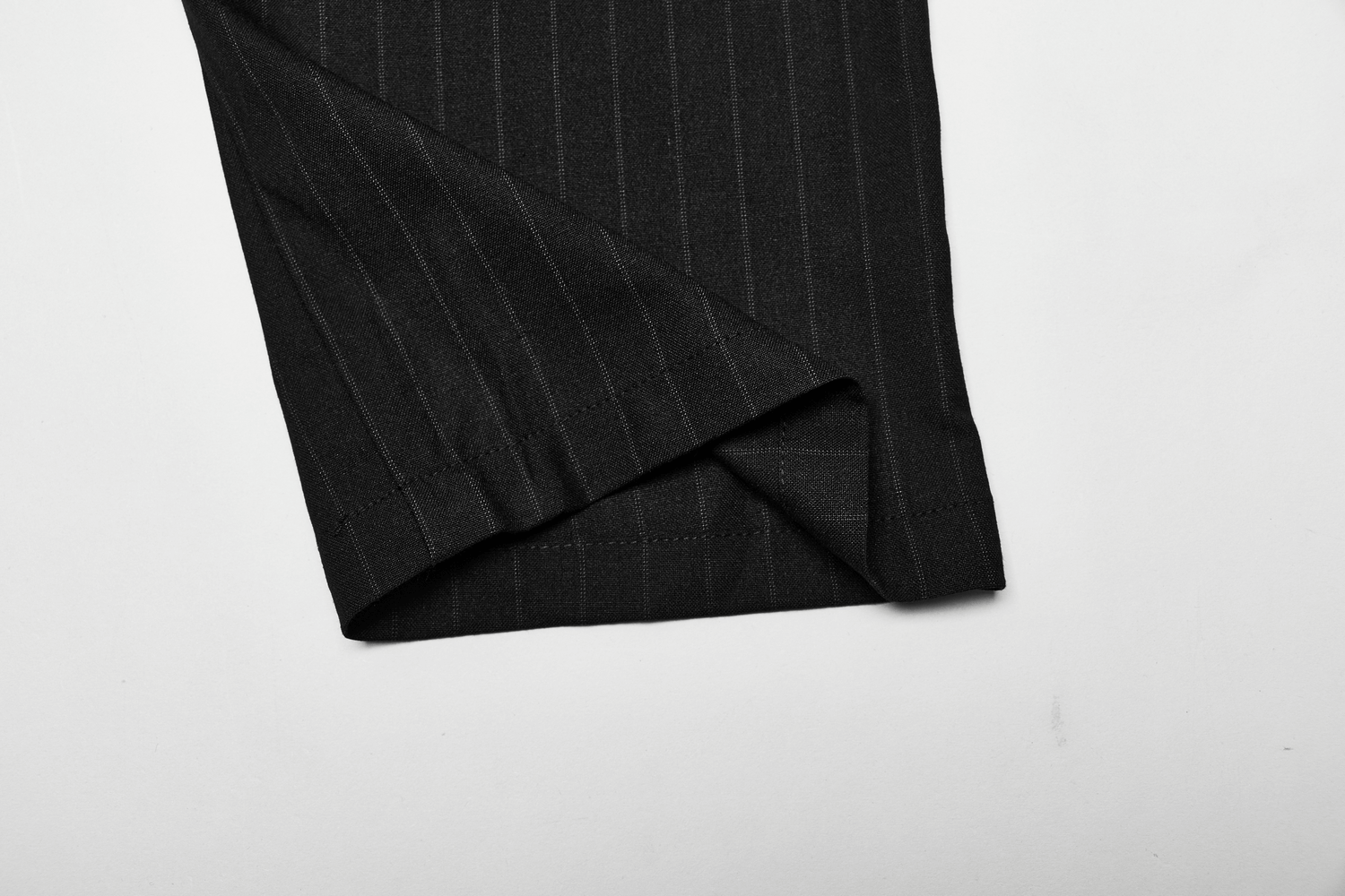Close-up of the hem of black striped steampunk pants, showcasing elegant fabric and tailored finish.