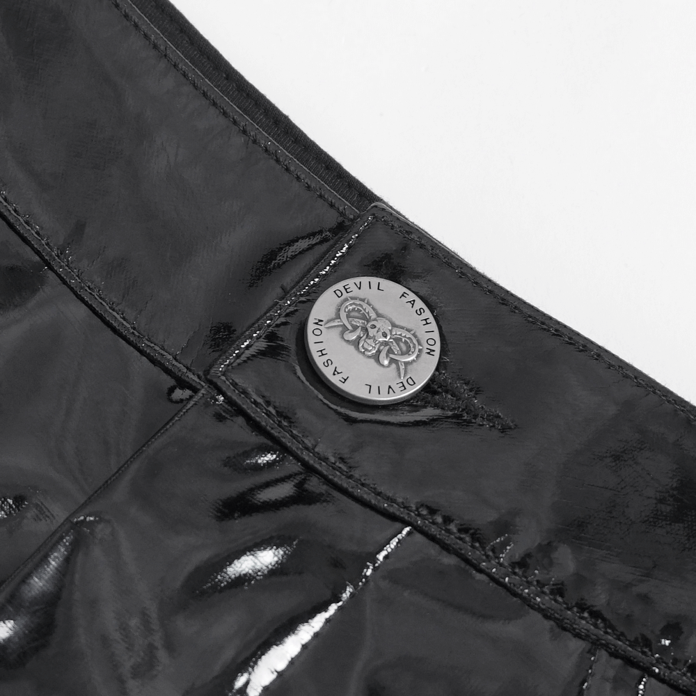 Close-up of glossy black shorts showcasing unique chain details and prominent metal badge for edgy punk fashion.