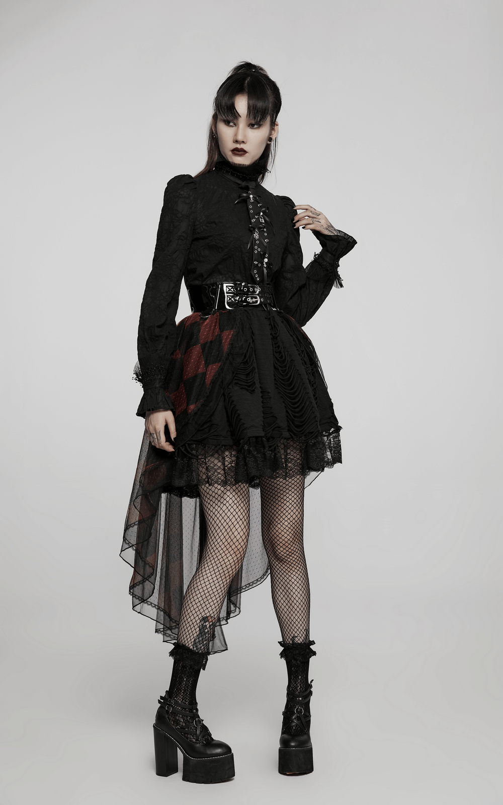 Fashionable model in a black outfit with a glossy corset belt and fishnet stockings, exuding punk rock style.