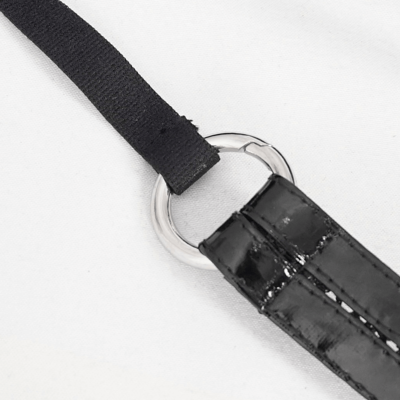 Close-up of a black strap with a shiny silver ring detail on a white background, showcasing stylish accessory design.