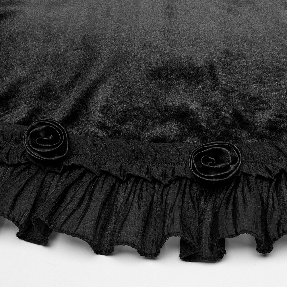 Close-up of black velvet dress showcasing lace detailing and ruffled hem with decorative roses.
