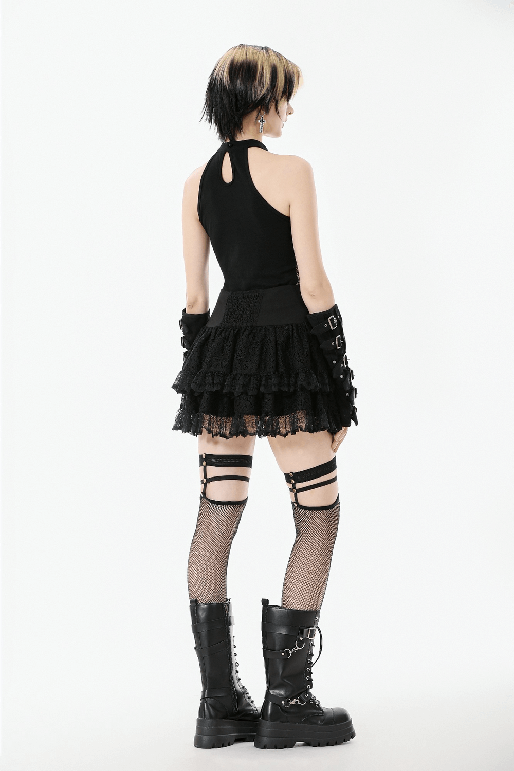Goth Halter Crop Top with Mesh Panels and Buckle paired with a layered black skirt and fishnet stockings.