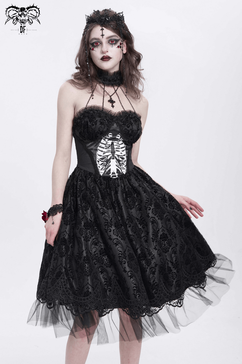 Model in a gothic halter dress with lace overlay, ribcage print, and tulle skirt, showcasing dark romantic style.
