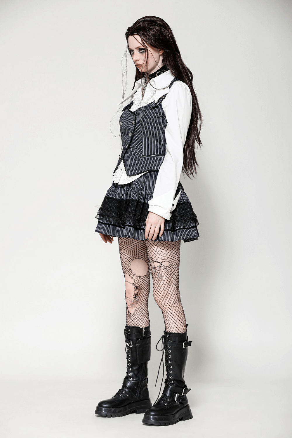 Gothic model in pinstripe double-breasted vest, layered skirt, and fishnet tights for edgy punk style.