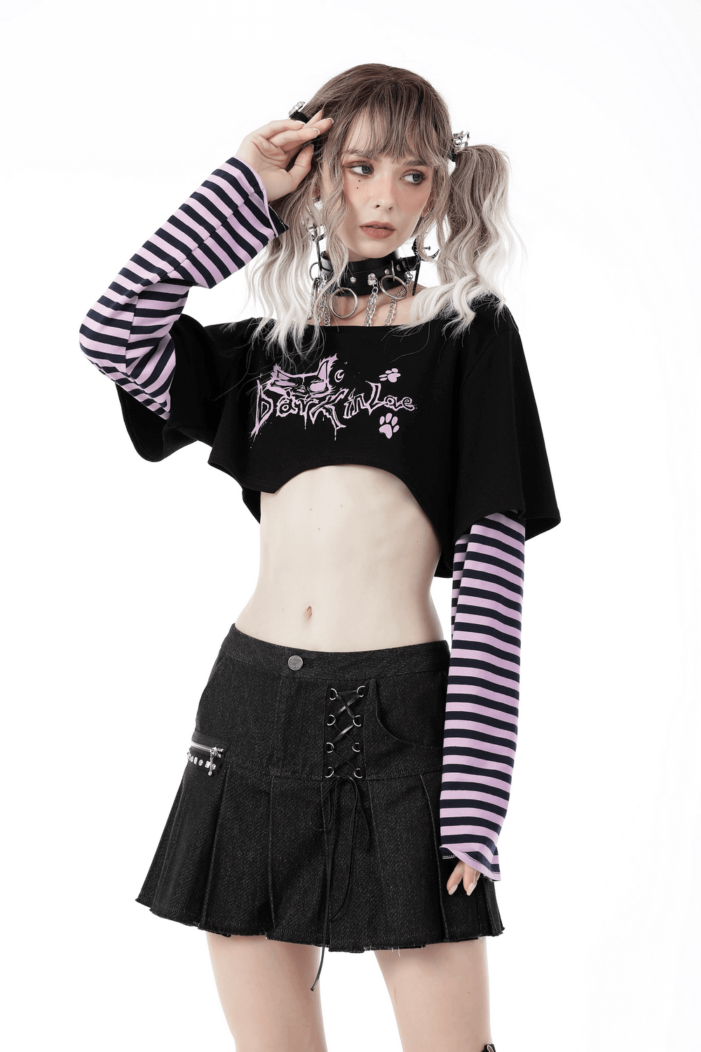 Goth punk crop top with Cheshire Cat graphic and striped sleeves, worn with a black skirt for a dark, trendy look.