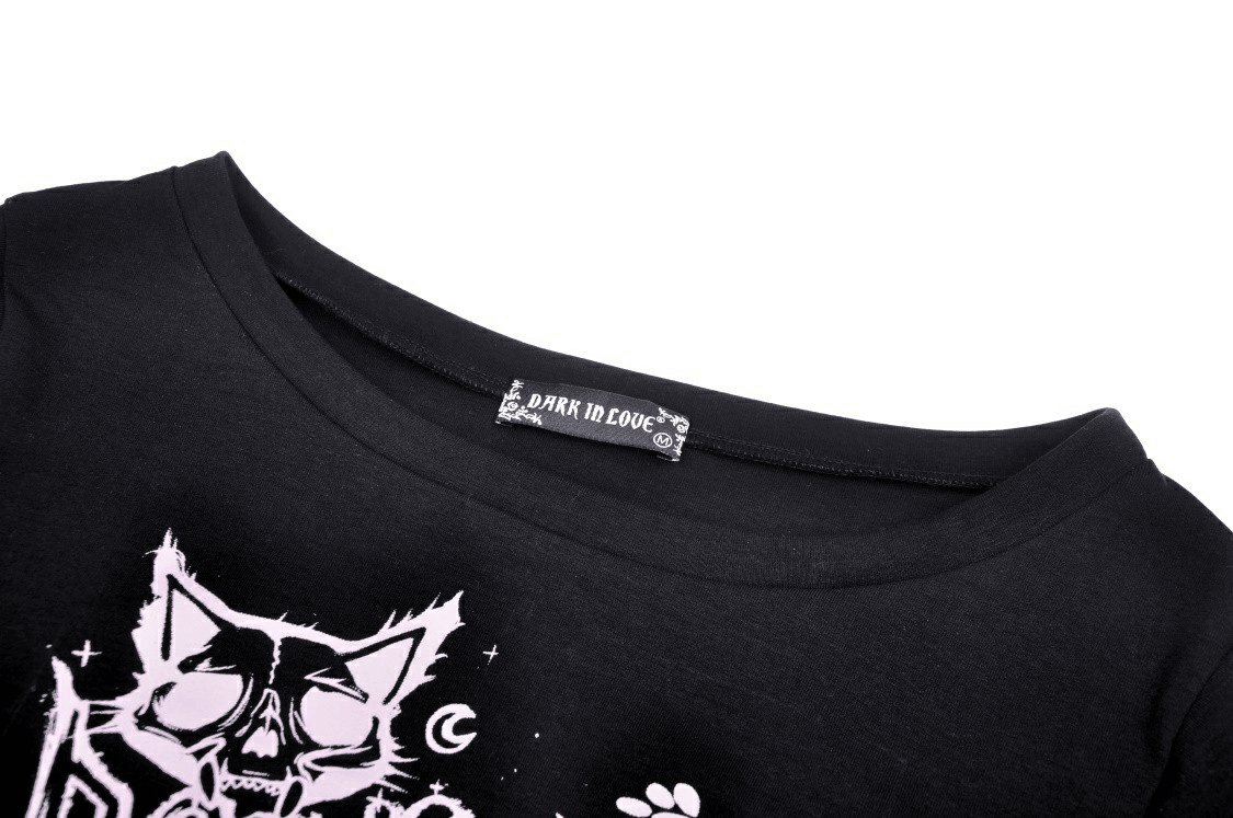 Close-up of goth punk crop top featuring Cheshire cat graphic and soft fabric with label 'Dark in Love'.
