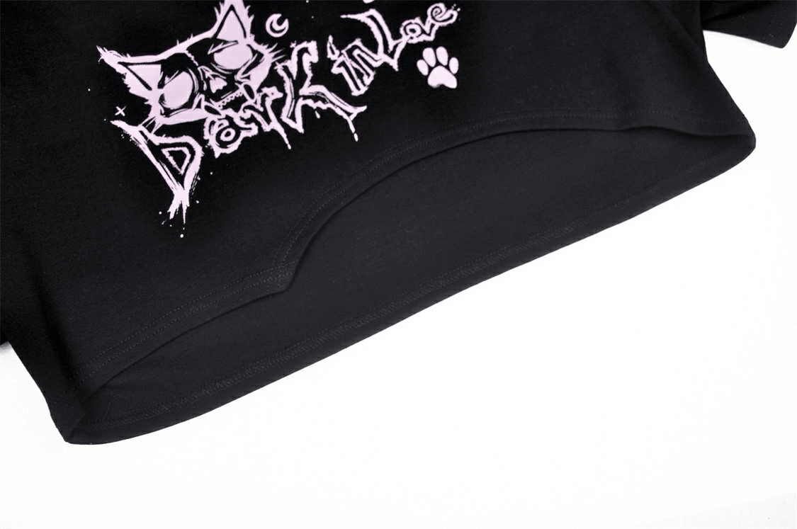 Close-up of goth punk crop top featuring playful Cheshire Cat graphic and 'Dark in Love' text in pink.