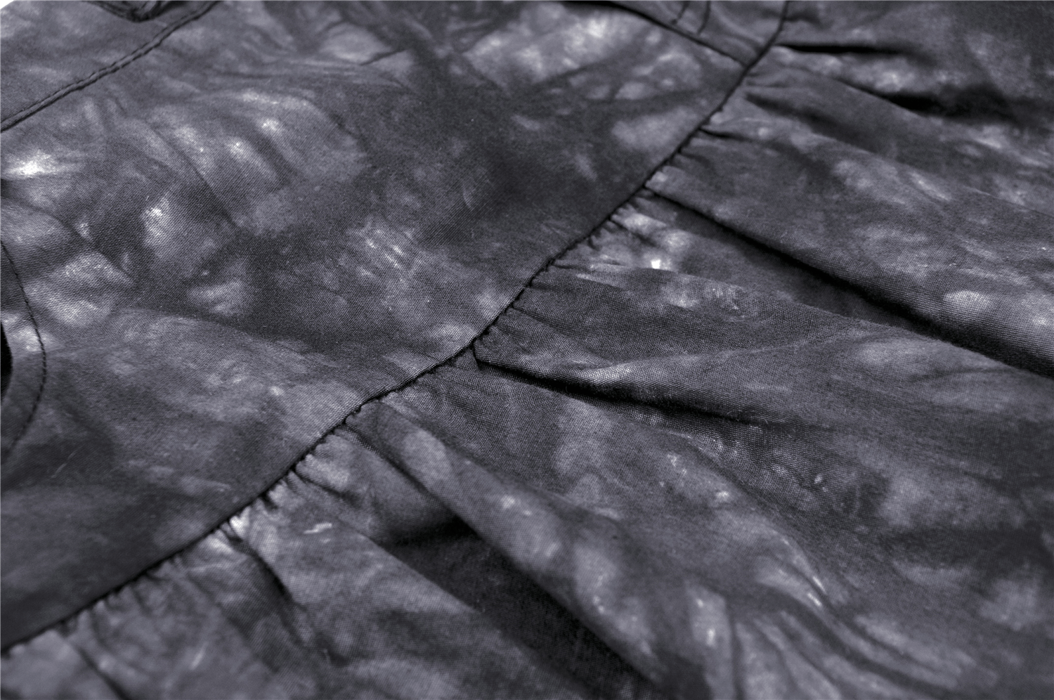 Close-up of black tie-dye fabric on a goth mini skirt with ruffles, showcasing edgy details.