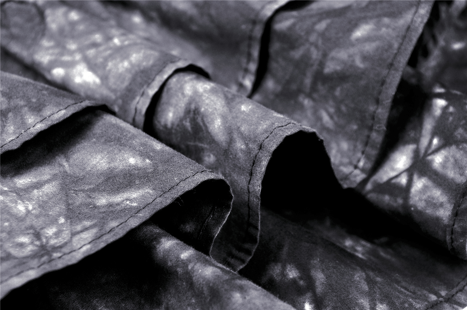 Close-up of black tie-dye fabric with ruffles, perfect for a goth mini skirt with chains.