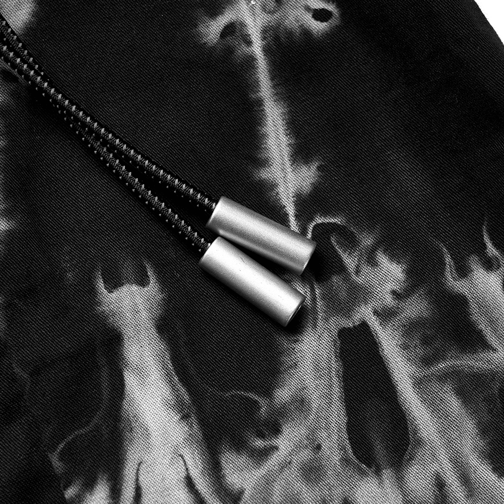 Close-up of tie-dyed black fabric with stylish silver drawstring ends, showcasing unique design details.