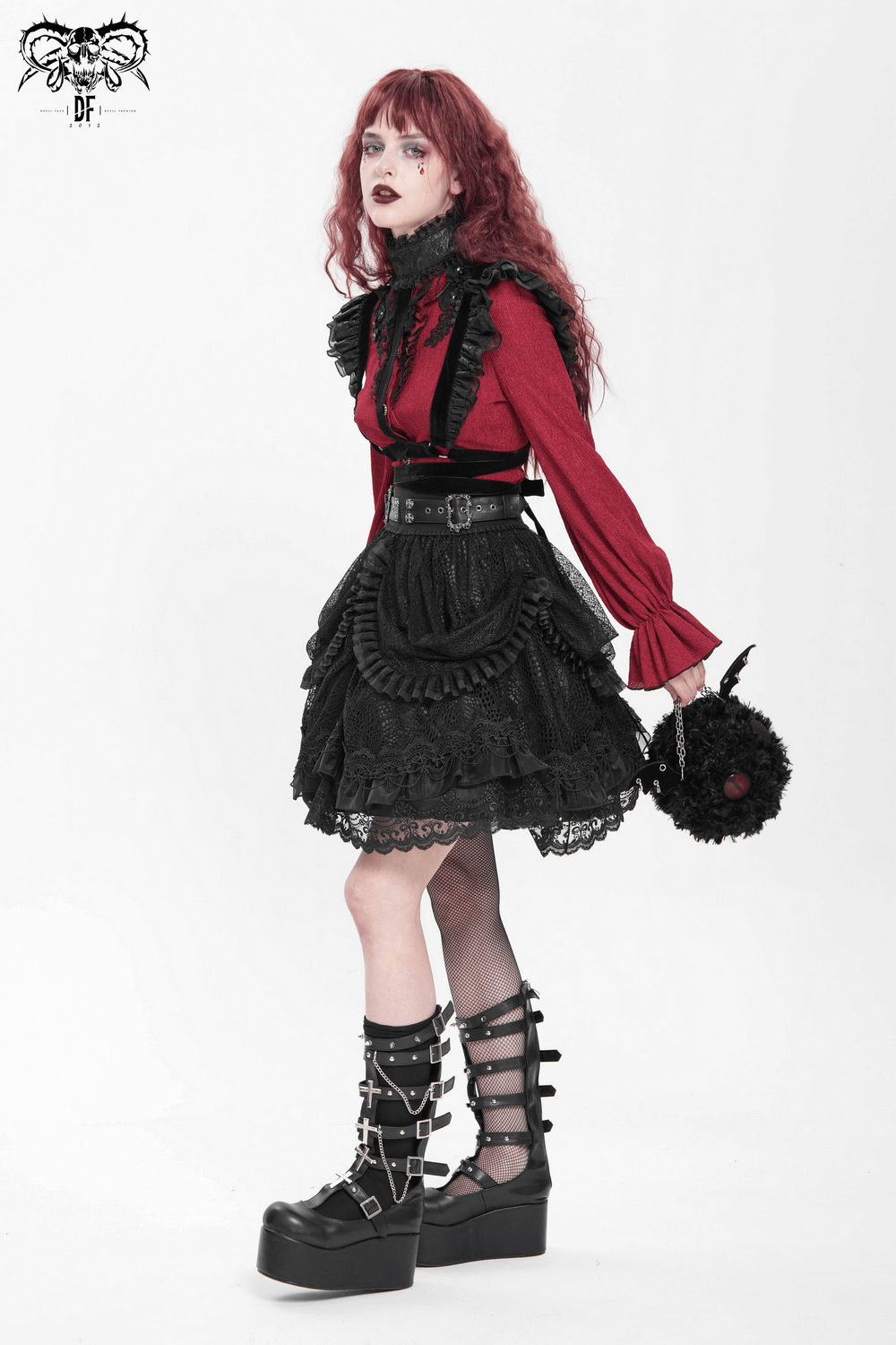 Gothic fashion model in red top and black skirt, wearing platform boots and holding a lace handbag.