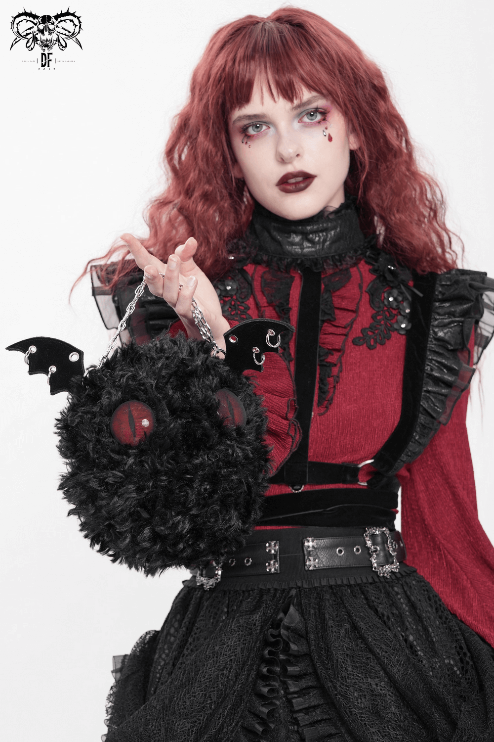 Gothic bat wing plush shoulder bag with red eyes, showcased by a model in a dramatic black and red outfit.