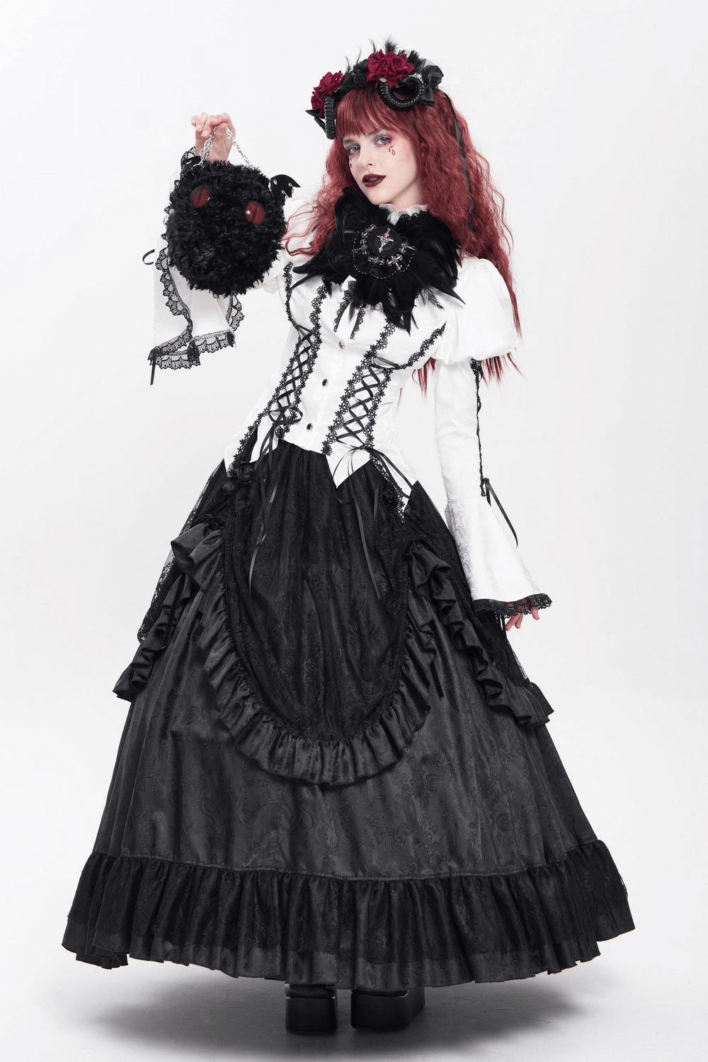Fashionable model in gothic attire holding a plush bat wing shoulder bag with red eyes and floral headpiece.
