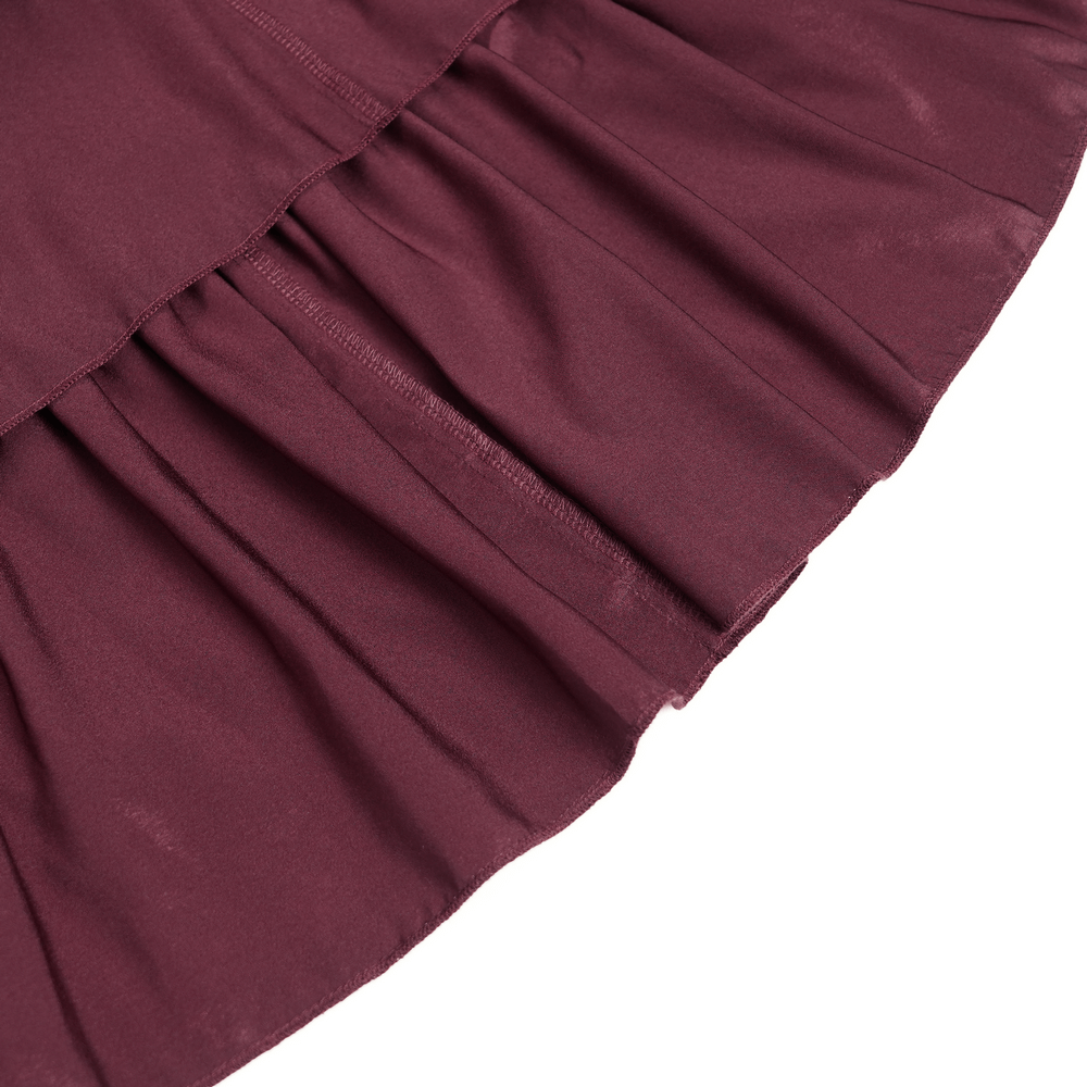 Close-up of burgundy maxi skirt's pleated hem showcasing its luxurious fabric and intricate design.