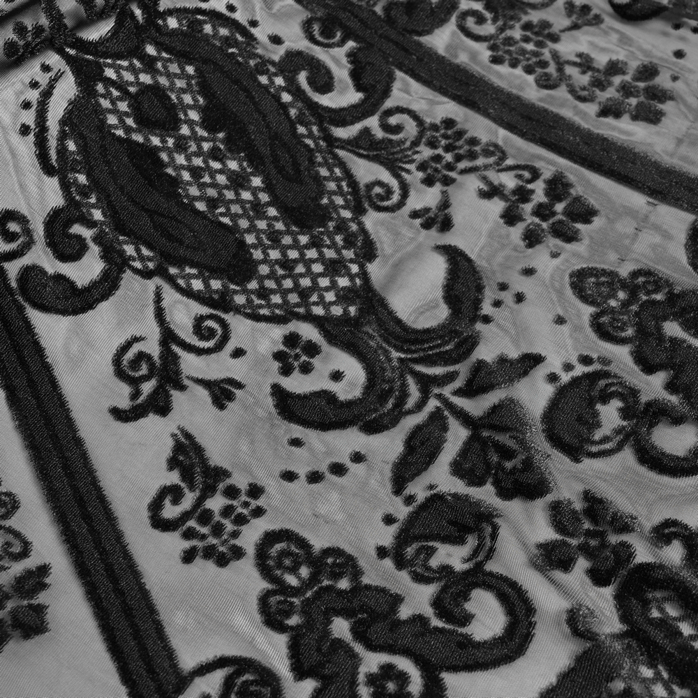 Intricate black lace overlay detail on a gothic Victorian skirt, showcasing elegant floral patterns and textures.