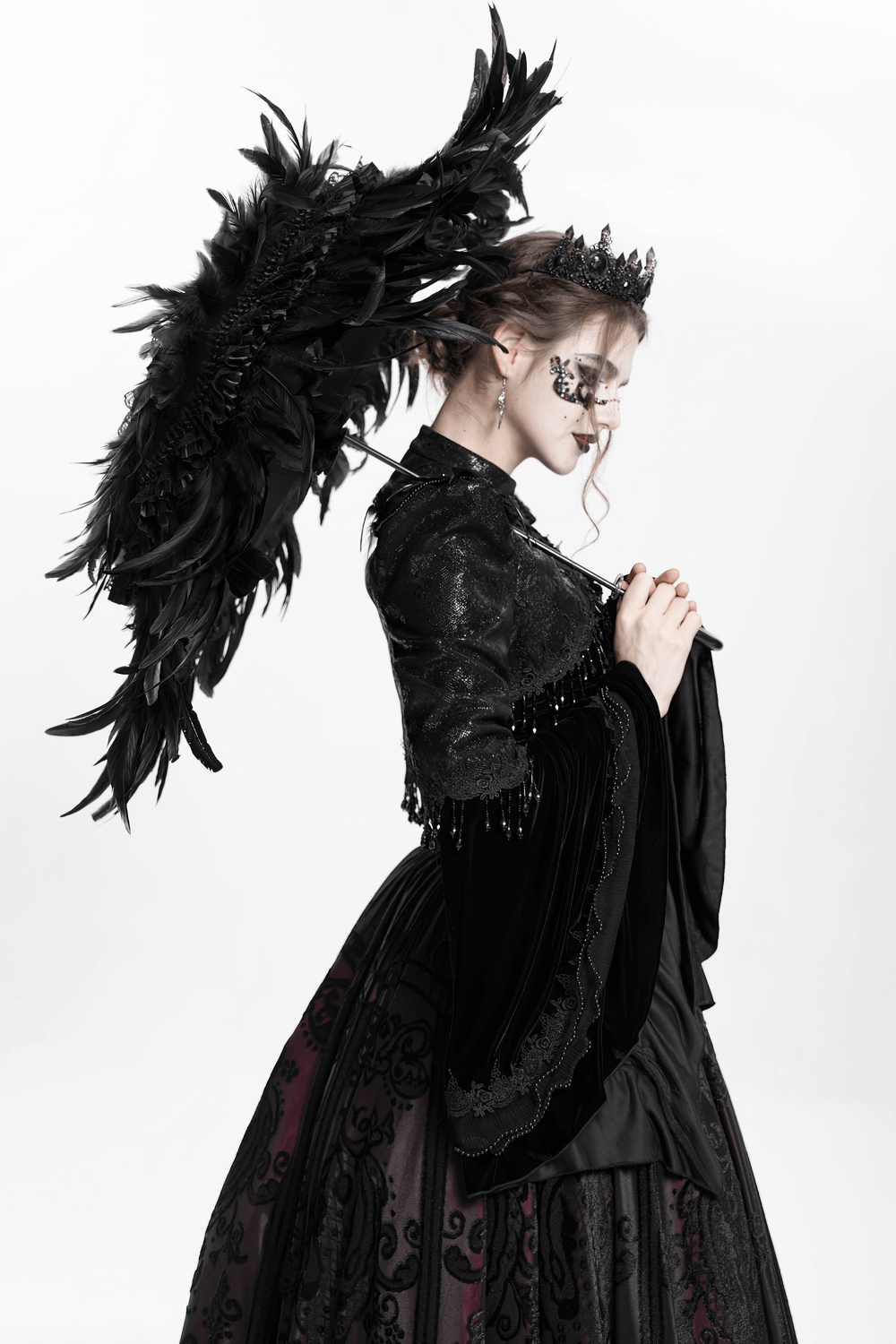 Model wearing a gothic black bolero shrug with dramatic bell sleeves, holding a feathered umbrella in an elegant pose.