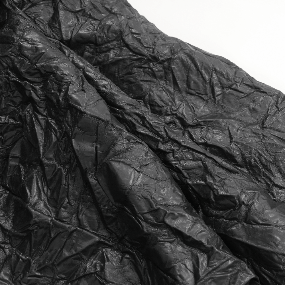 Close-up of crinkled black leather texture, showcasing a unique gothic style perfect for punk rock fashion.