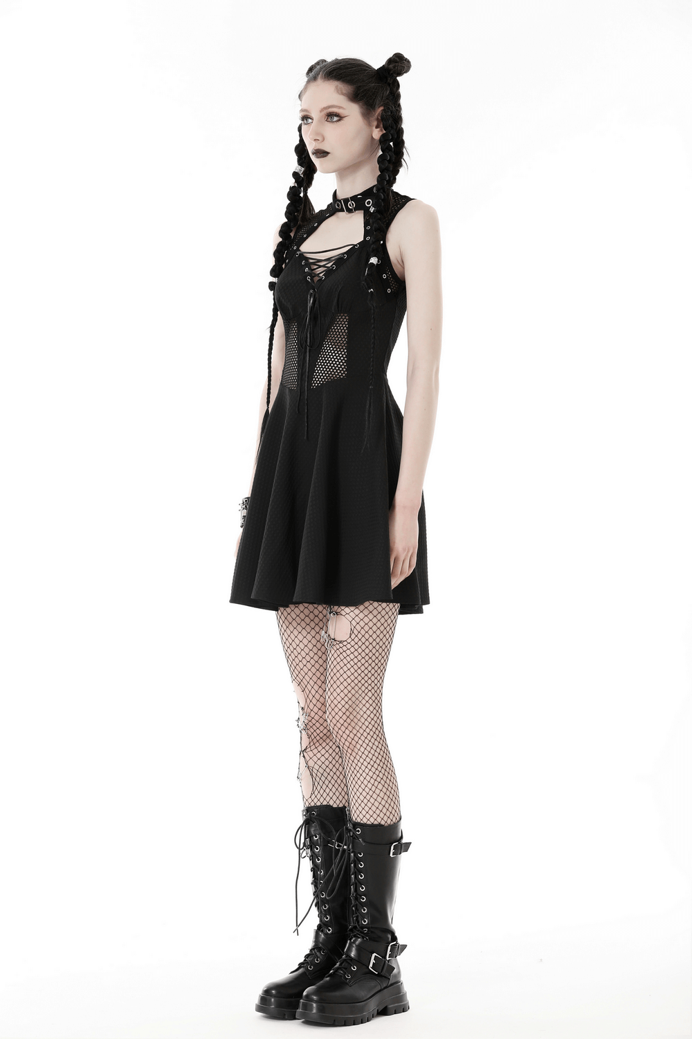 Gothic black mini dress with fishnet details, lace-up front, and rivet accents, paired with edgy lace-up boots.