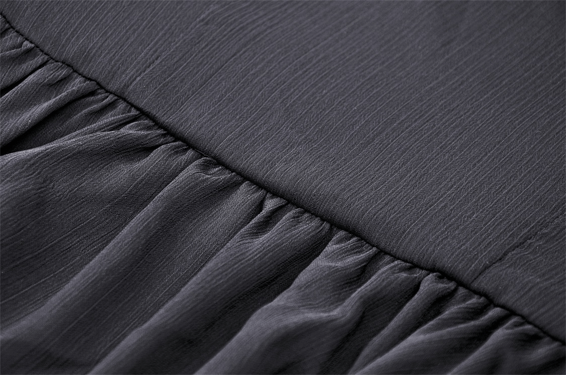 Close-up of the textured fabric featuring pleats and draping in a sleek dark shade, perfect for a gothic dress.