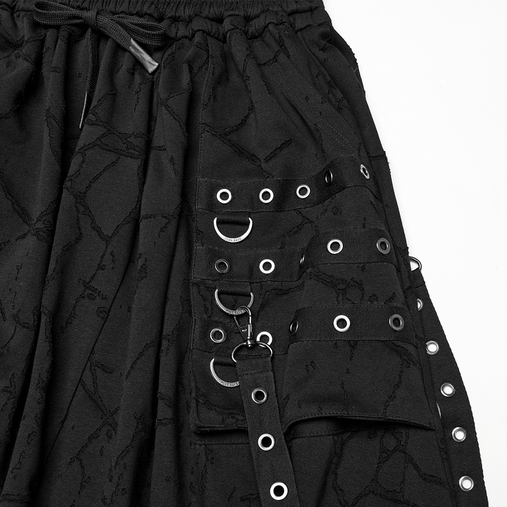 Close-up of gothic black drop crotch pants with eyelet straps and bold pockets, showcasing edgy punk style.