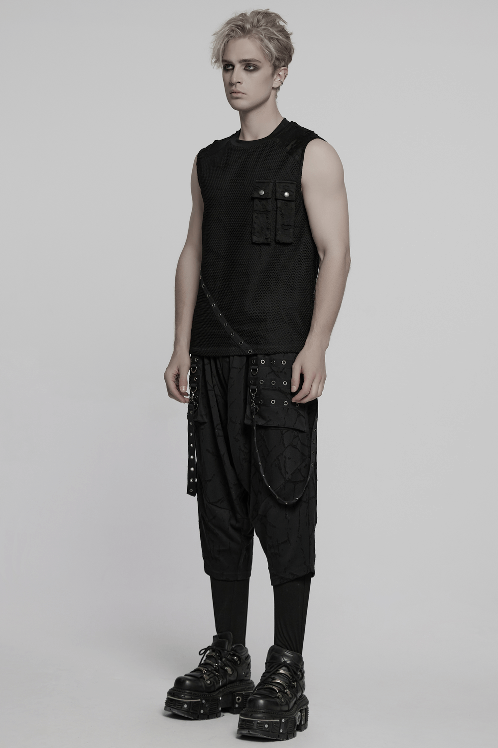 Male model wearing gothic black drop crotch pants with eyelet straps and a textured sleeveless top.