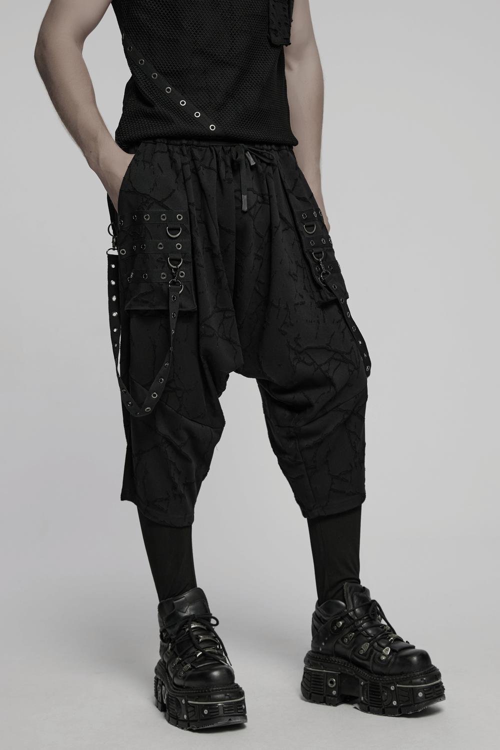 Gothic black drop crotch pants with eyelet straps and bold pockets, styled for male punk fashion enthusiasts.