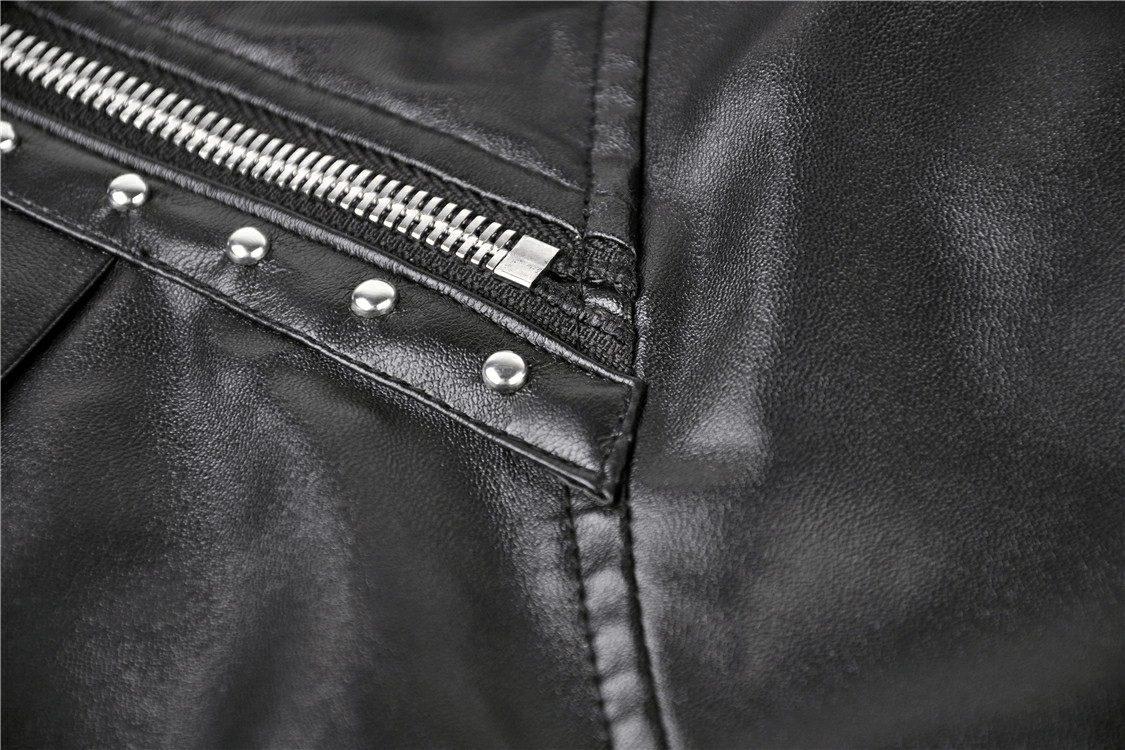 Close-up of a black faux leather skirt featuring a zip and metallic studs, showcasing edgy punk style details.
