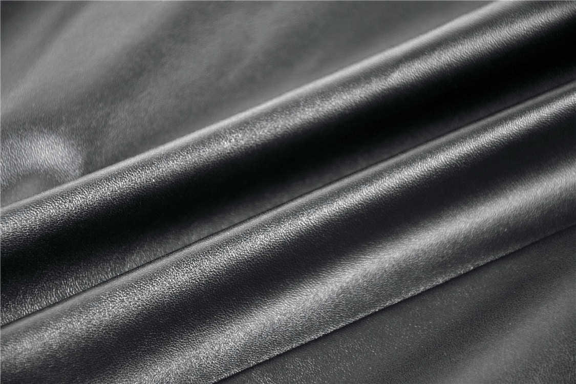 Close-up of black faux leather fabric showcasing a smooth, sleek texture, perfect for edgy gothic fashion.