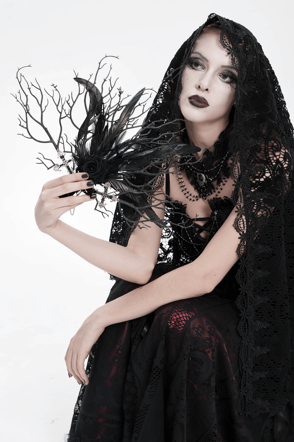 Gothic Black Feather and Twig Hand Fan with Cross Charms held by a model in dramatic black attire.