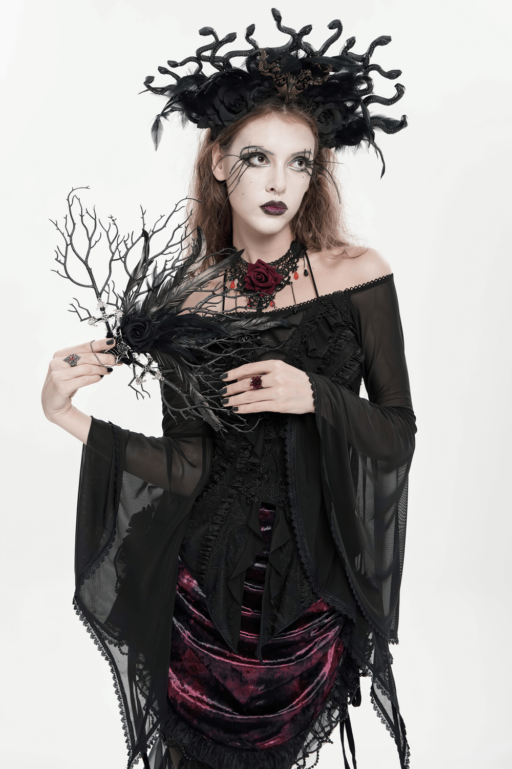 Gothic Black Feather and Twig Hand Fan with Cross Charms held by a heavily styled gothic model in dark attire.