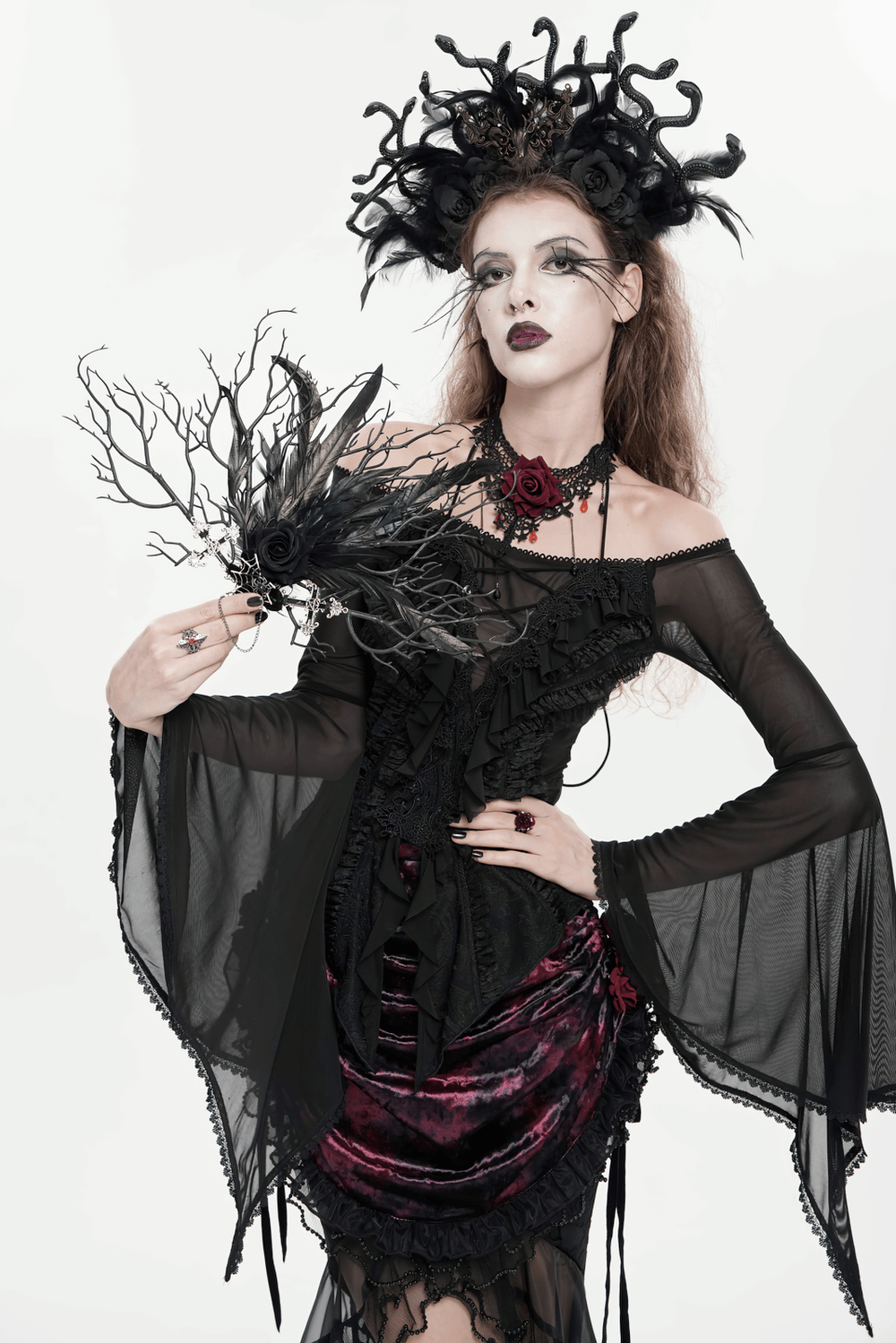 Gothic Black Feather and Twig Hand Fan with Cross Charms held by a gothic model in dark attire.