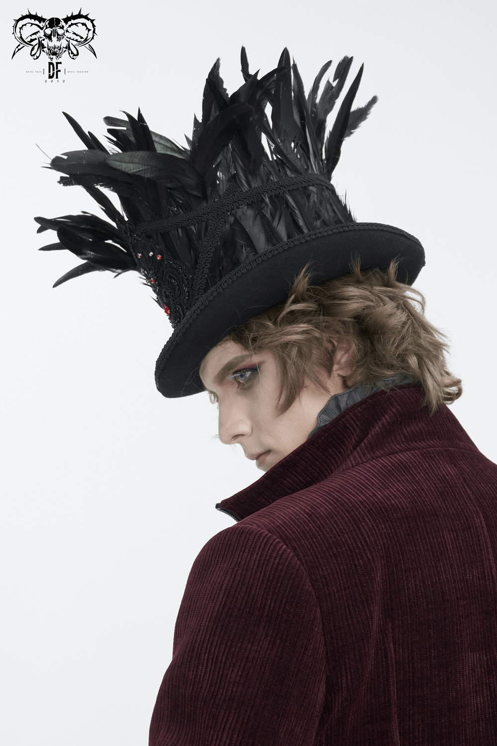 Gothic black feathered top hat with embroidered accents and red jewel details, worn elegantly by a model.