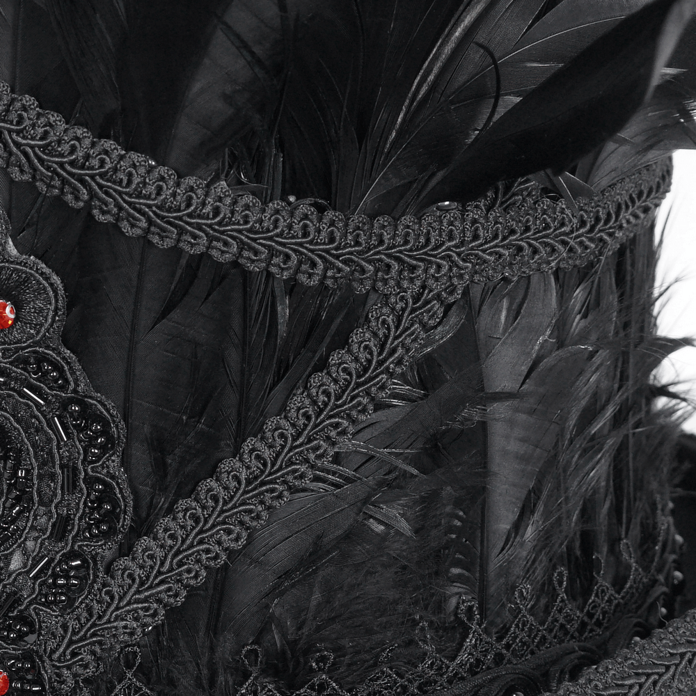 Close-up of gothic black feathered top hat with intricate embroidery and red jewel accents.