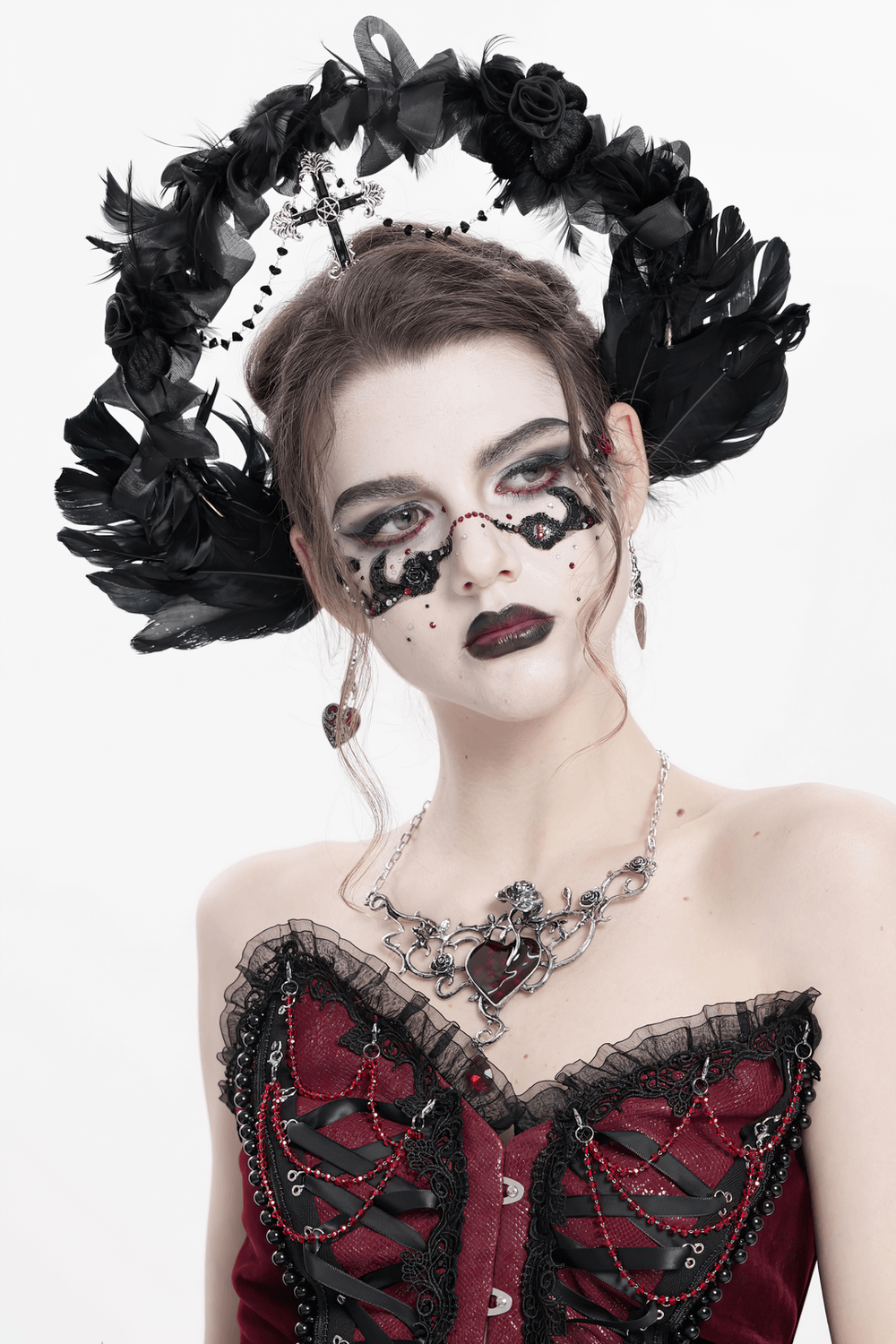 Gothic black halo crown with feathers and cross, worn by model in dramatic makeup and elegant attire.