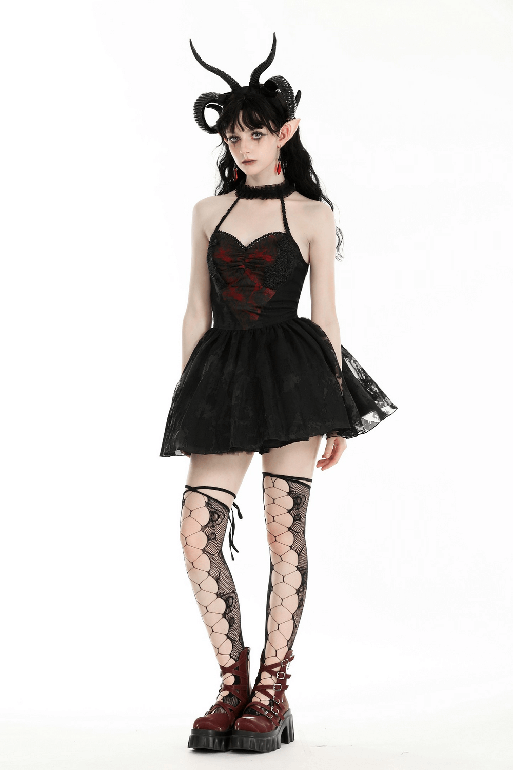 Model in a gothic black halter dress with lace, ruffles, and horned hairstyle, showcasing dark fashion elegance.