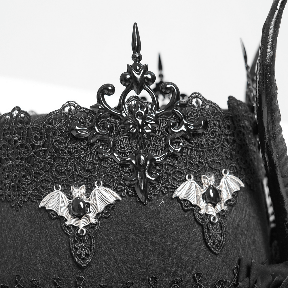 Close-up of ornate black lace and bat embellishments on a gothic horned top hat.