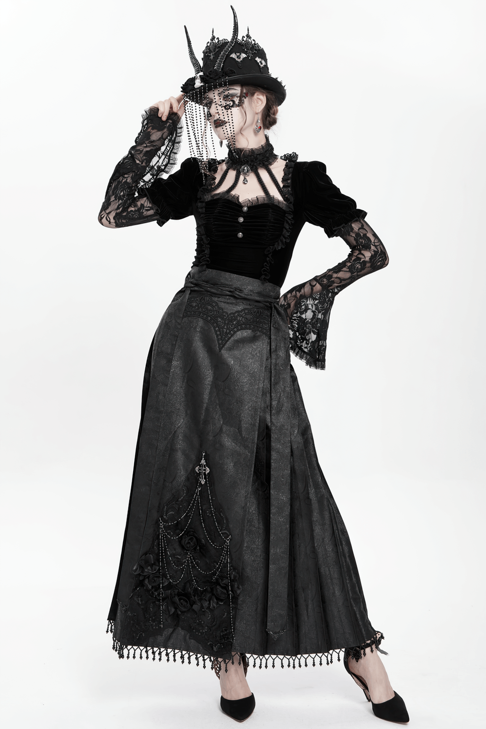Gothic fashion model in black lace top and elegant long skirt with dramatic black horned top hat.