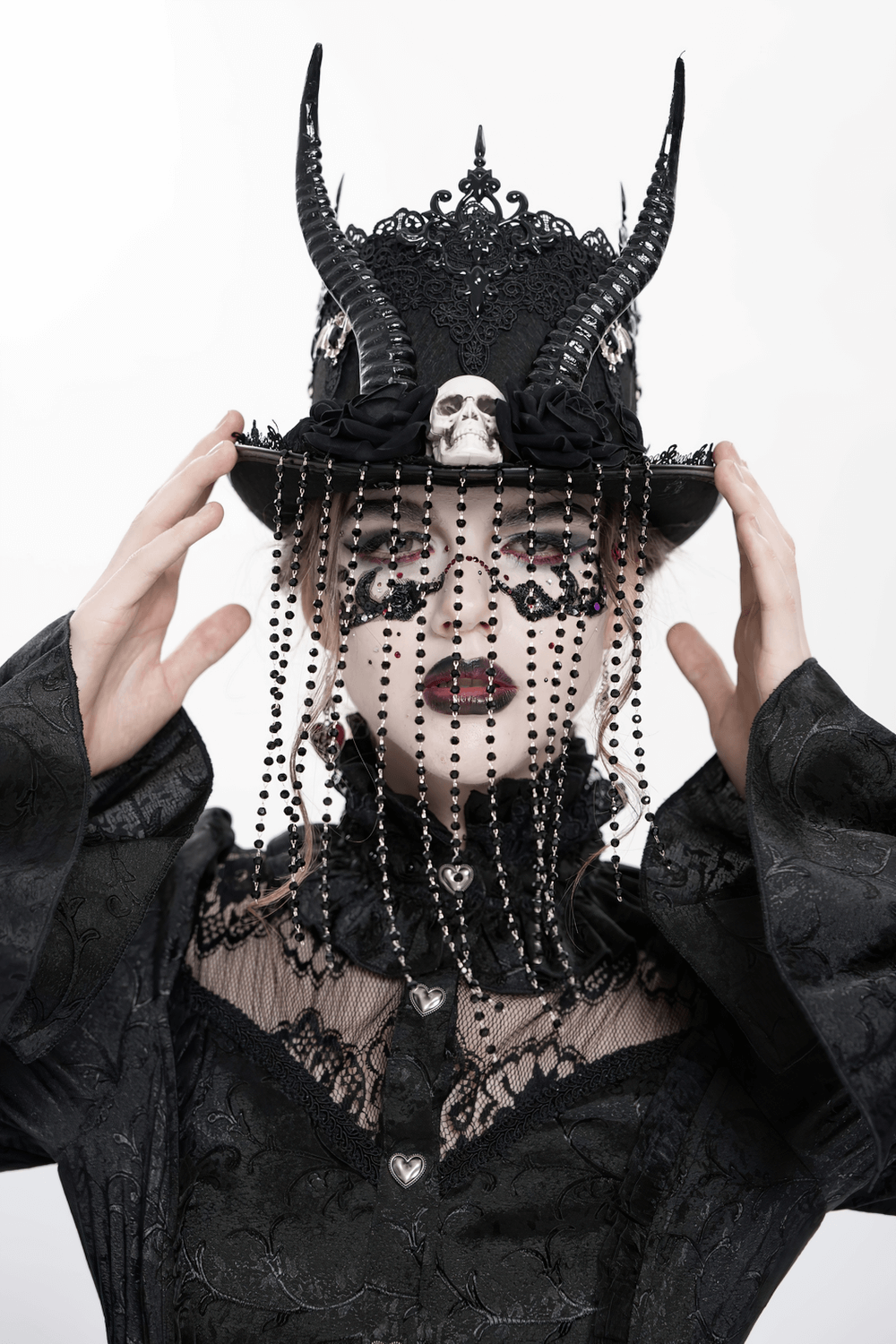 Gothic black horned top hat with skull, roses, and lace details, worn by model in dark attire.