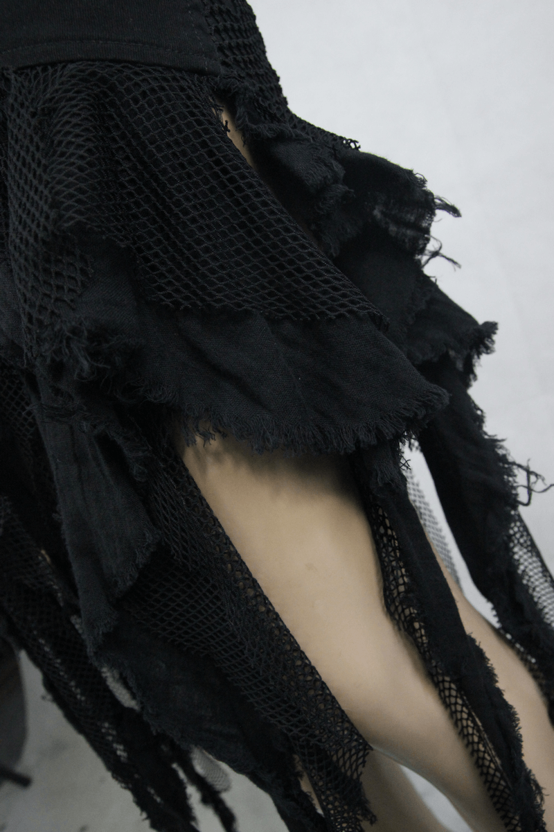 Close-up of a women's gothic black irregular skirt featuring torn denim and net fabric layers.