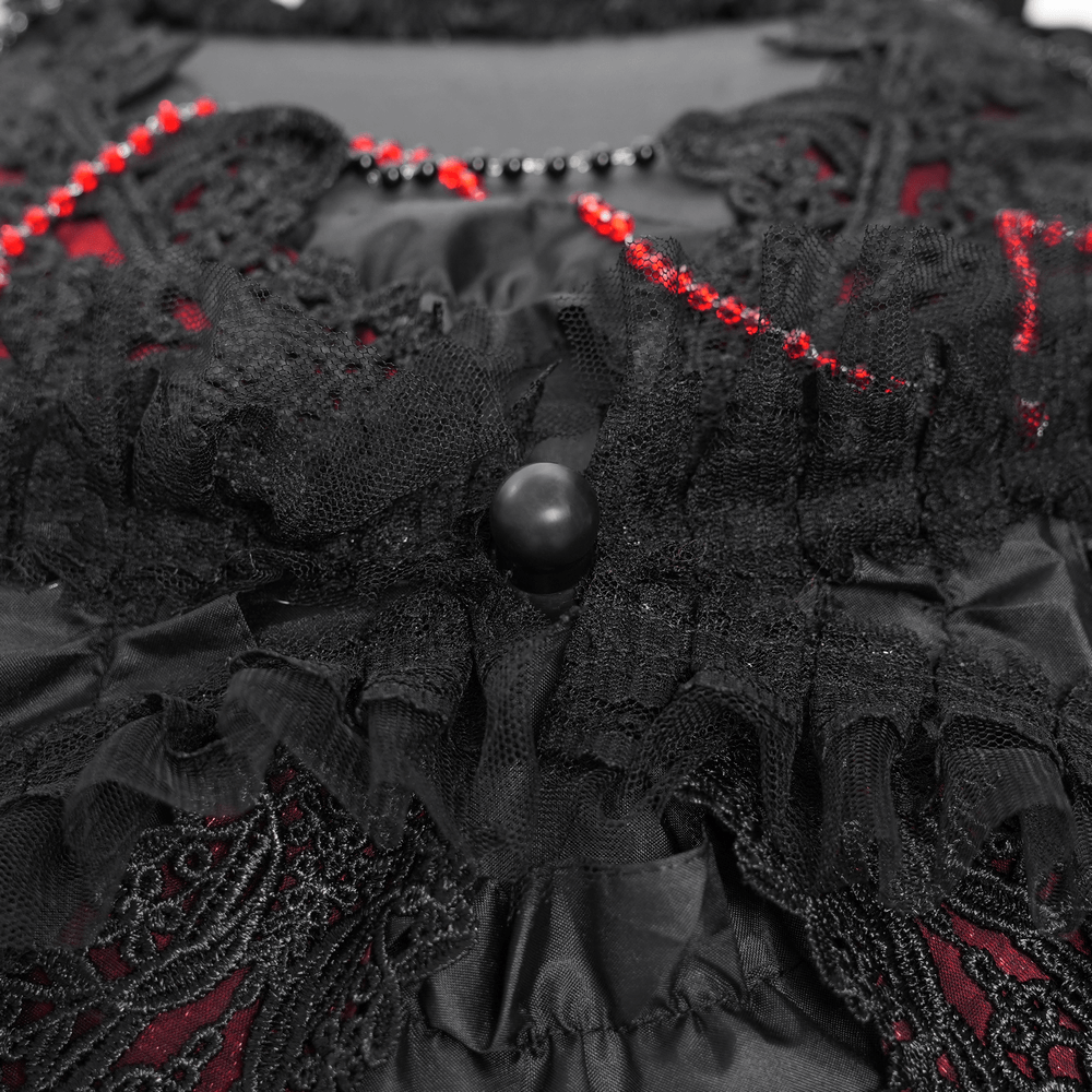 Close-up of gothic black lace, red bead accents, and ruffled fabric detail, showcasing vintage elegance.