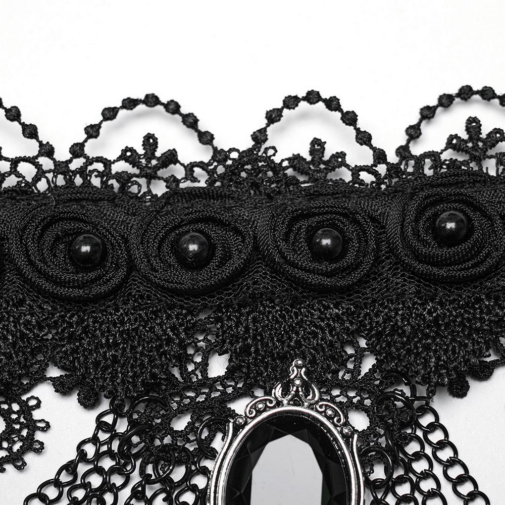 Close-up of Gothic black lace collar with intricate designs and gemstone pendant, showcasing elegant craftsmanship.