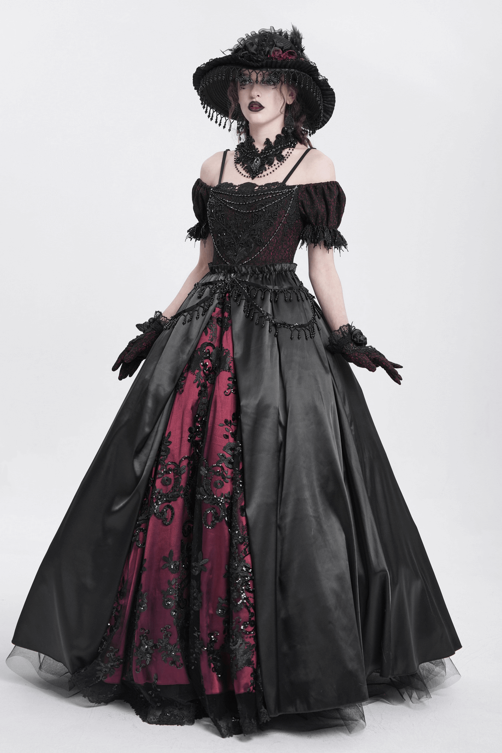 Elegant gothic woman in a black and red embroidered gown with a wide-brimmed hat and lace choker necklace.