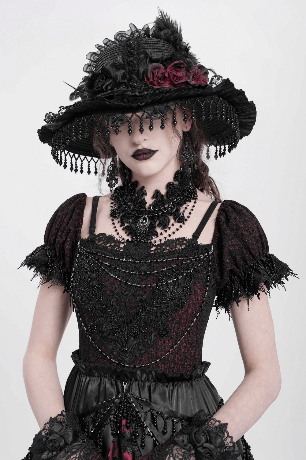 Model in gothic attire featuring a black lace choker, embellished hat, and dark floral accents for a dramatic look.