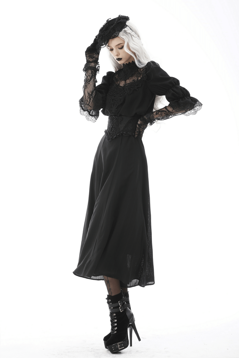 Elegant model in a gothic black lace outfit, featuring ruffled sleeves and high-heeled boots.