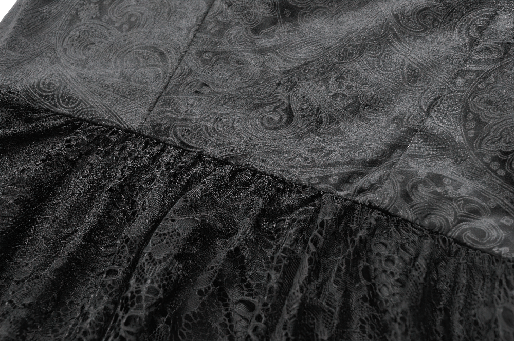 Close-up of intricate black lace and satin fabric on a gothic Victorian dress with layered tiers.