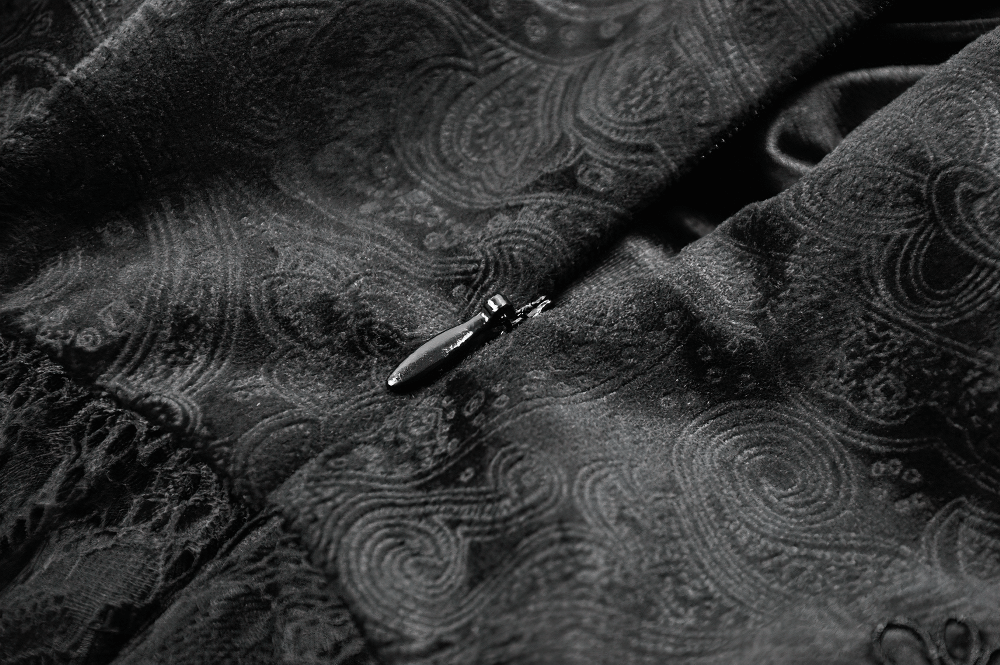 Close-up of the intricate black lace fabric featuring elegant patterns and a delicate zipper detail.